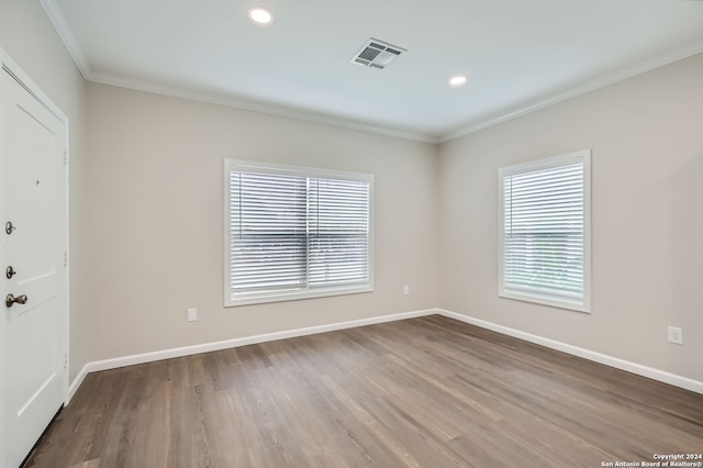 spare room featuring hardwood / wood-style floors, crown molding, and a healthy amount of sunlight