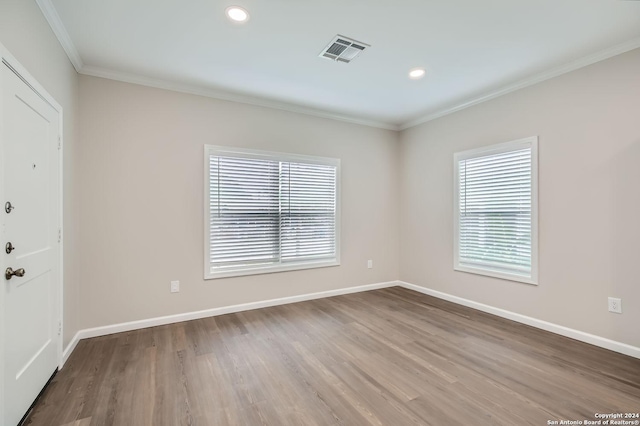 empty room with baseboards, wood finished floors, ornamental molding, and recessed lighting