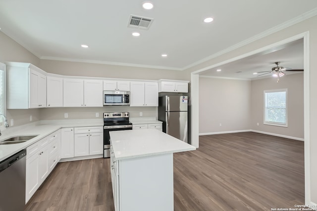 kitchen with a kitchen island, sink, white cabinets, appliances with stainless steel finishes, and light hardwood / wood-style floors