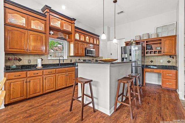 kitchen featuring a kitchen island, appliances with stainless steel finishes, a kitchen breakfast bar, dark wood-type flooring, and pendant lighting