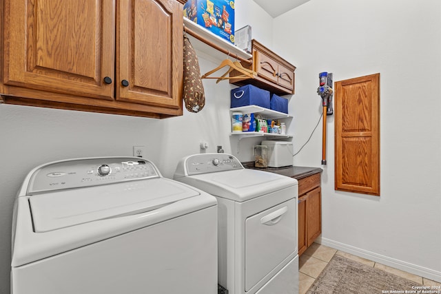 laundry area with independent washer and dryer, cabinets, and light tile patterned flooring