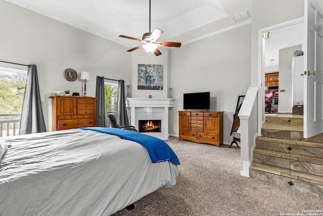 bedroom featuring carpet, a tiled fireplace, multiple windows, and ceiling fan