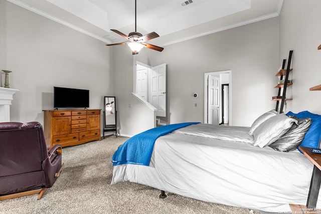 bedroom featuring carpet, ceiling fan, a tray ceiling, ornamental molding, and a towering ceiling