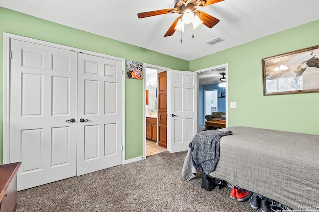 bedroom featuring light carpet, ensuite bathroom, and ceiling fan