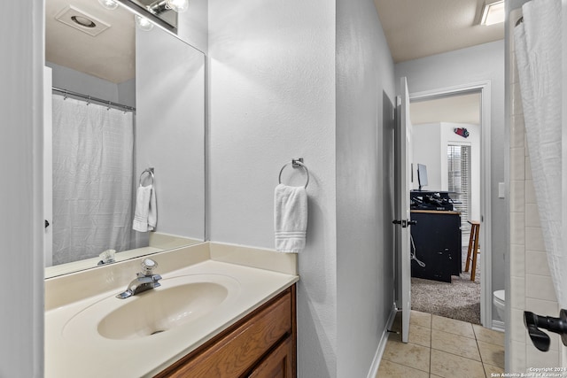 bathroom with vanity, toilet, tile patterned floors, and a textured ceiling