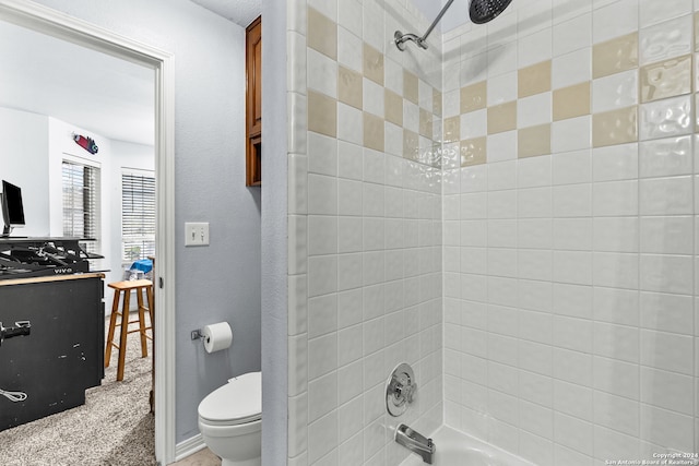 bathroom featuring toilet and tiled shower / bath combo