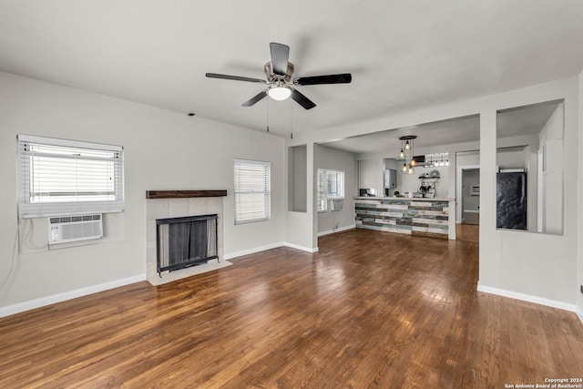 unfurnished living room featuring cooling unit, dark wood-type flooring, a tile fireplace, and ceiling fan