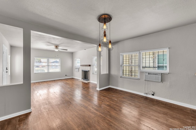 unfurnished living room with ceiling fan, a textured ceiling, cooling unit, and dark hardwood / wood-style floors