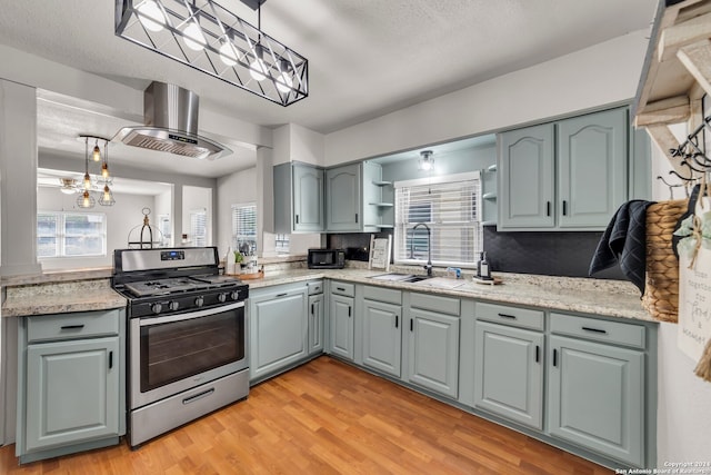 kitchen with stainless steel range with gas stovetop, sink, light hardwood / wood-style flooring, and range hood