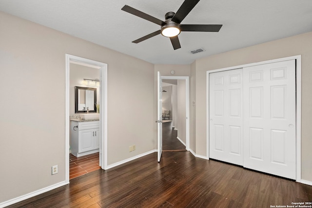 unfurnished bedroom with a closet, dark hardwood / wood-style floors, ensuite bath, and ceiling fan