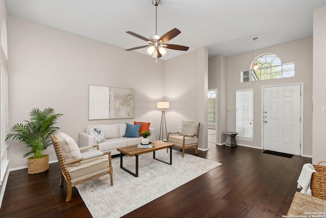 living room with ceiling fan, a high ceiling, and dark hardwood / wood-style floors