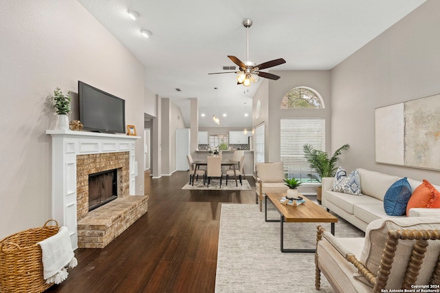 living room with dark wood-type flooring, ceiling fan, high vaulted ceiling, and a fireplace