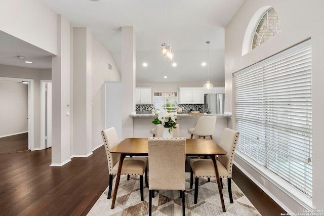 dining area featuring dark wood-type flooring and high vaulted ceiling