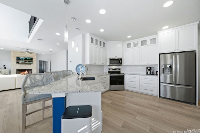 kitchen featuring kitchen peninsula, appliances with stainless steel finishes, a breakfast bar, a fireplace, and sink