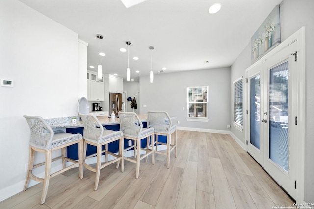 dining area featuring french doors, light hardwood / wood-style flooring, and a healthy amount of sunlight