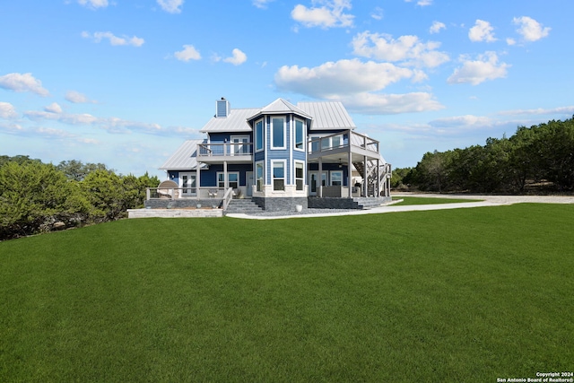 rear view of property with a yard and a balcony