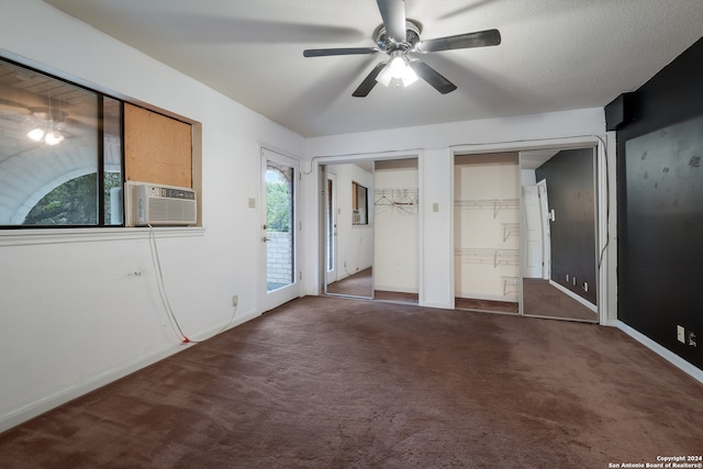 unfurnished bedroom with two closets, ceiling fan, dark colored carpet, and cooling unit