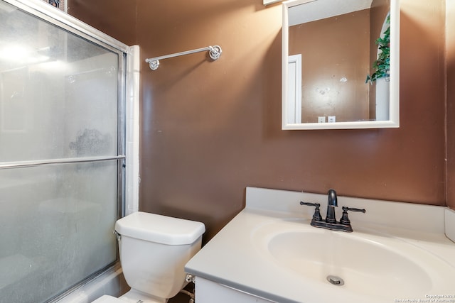 bathroom with vanity, toilet, and a shower with door