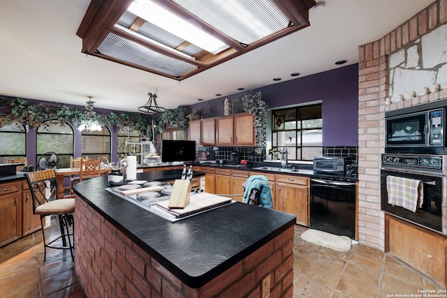 kitchen with a center island, sink, backsplash, decorative light fixtures, and black appliances