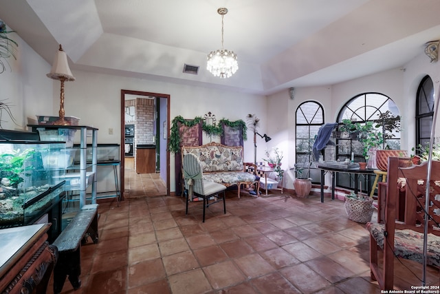 sitting room featuring a raised ceiling and an inviting chandelier