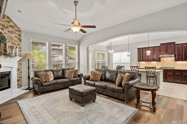 living room with vaulted ceiling, a fireplace, wood-type flooring, and ceiling fan