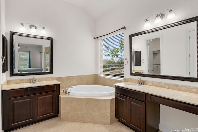 bathroom with vanity, vaulted ceiling, tiled bath, and tile patterned floors