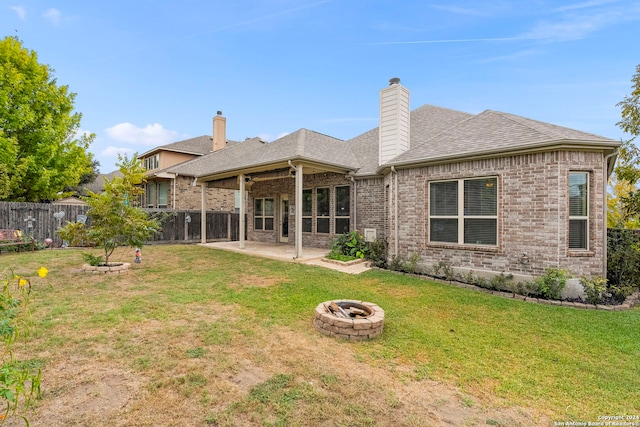 rear view of property featuring a patio area, a fire pit, and a lawn