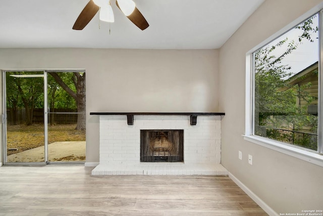 unfurnished living room with light hardwood / wood-style flooring, a brick fireplace, and ceiling fan