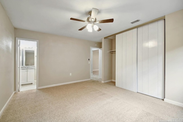 unfurnished bedroom with connected bathroom, ceiling fan, light carpet, and a closet