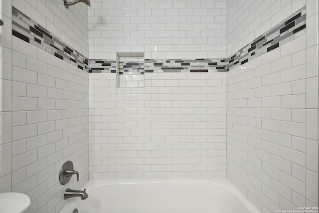 bathroom featuring toilet and tiled shower / bath combo