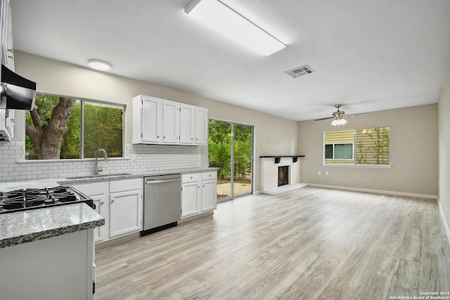 kitchen featuring light stone countertops, sink, stainless steel dishwasher, and white cabinets