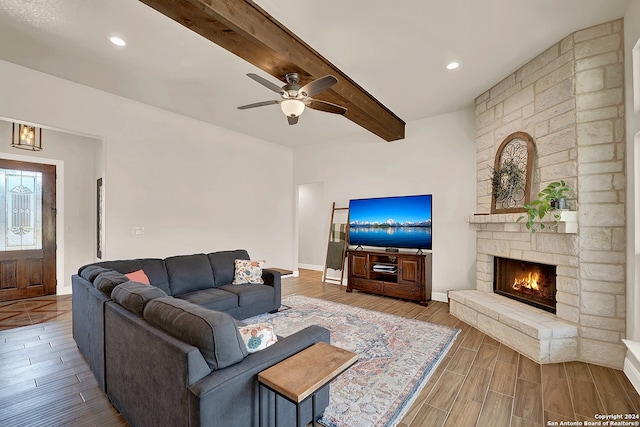 living room with ceiling fan, hardwood / wood-style flooring, beamed ceiling, and a fireplace