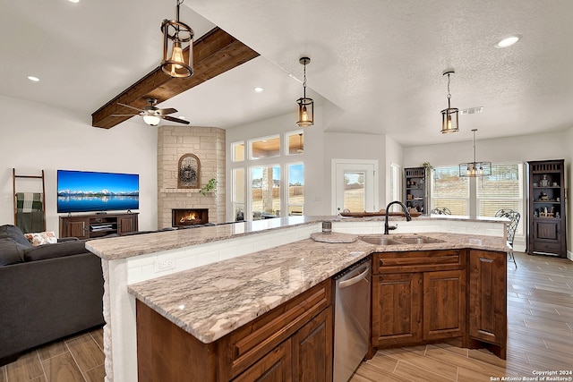 kitchen with light stone countertops, sink, an island with sink, light hardwood / wood-style floors, and stainless steel dishwasher