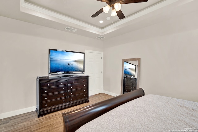 bedroom featuring light hardwood / wood-style floors, a raised ceiling, and ceiling fan