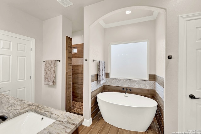 bathroom with vanity, crown molding, plus walk in shower, and hardwood / wood-style flooring