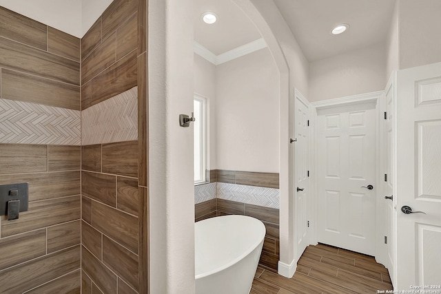 bathroom with ornamental molding, hardwood / wood-style flooring, and a bath