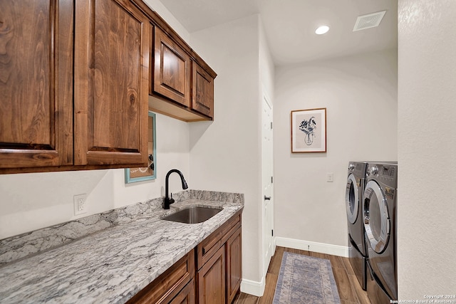 clothes washing area featuring sink, dark wood-type flooring, independent washer and dryer, and cabinets