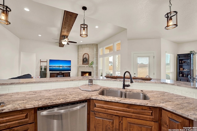 kitchen with a stone fireplace, beam ceiling, sink, decorative light fixtures, and stainless steel dishwasher