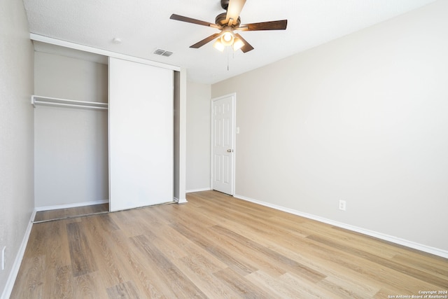 unfurnished bedroom featuring light hardwood / wood-style floors, a closet, a textured ceiling, and ceiling fan