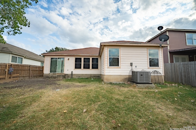 back of property featuring cooling unit and a yard