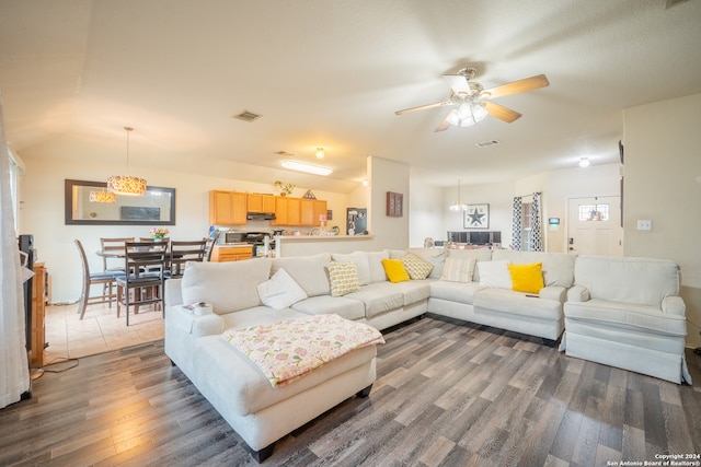 living room featuring ceiling fan with notable chandelier and dark hardwood / wood-style floors