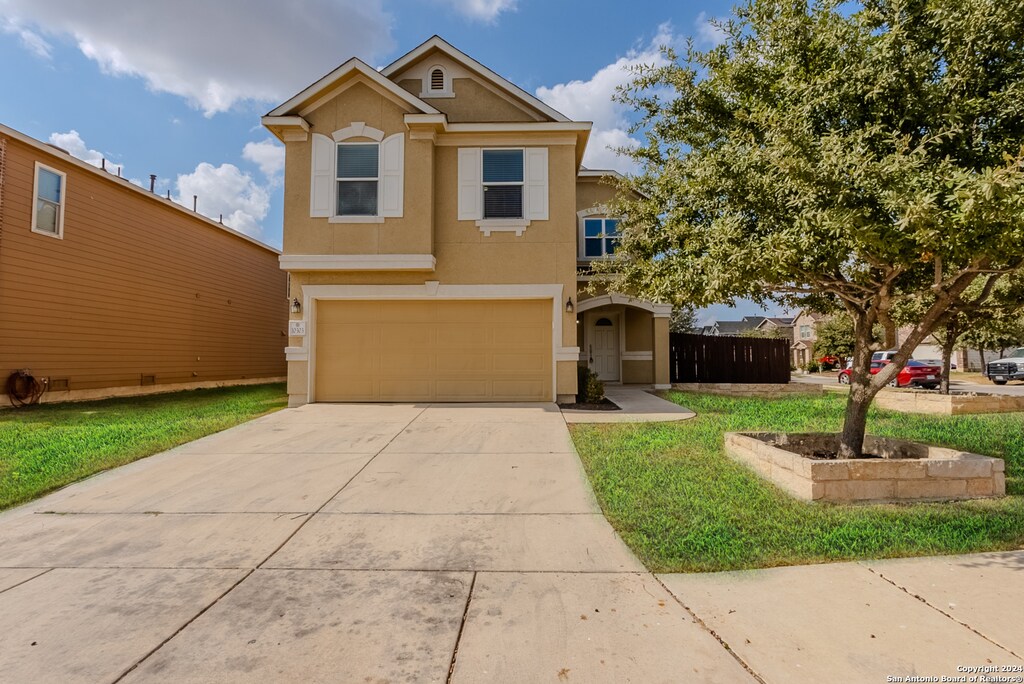 traditional-style home featuring stucco siding, a garage, and driveway