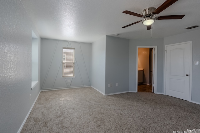 spare room featuring light carpet, a textured ceiling, and ceiling fan