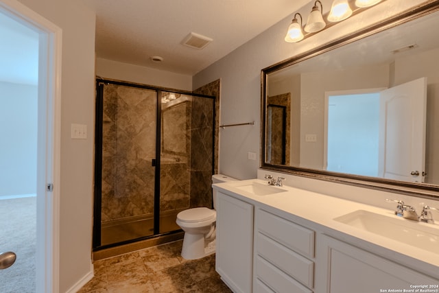 bathroom with toilet, vanity, and a shower with door