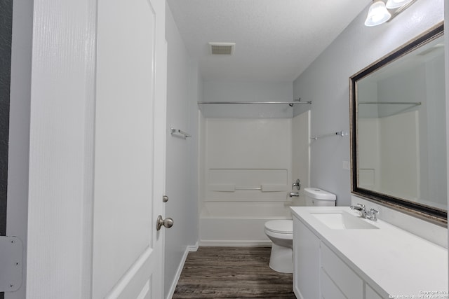 full bathroom with a textured ceiling, hardwood / wood-style floors, toilet, vanity, and tub / shower combination