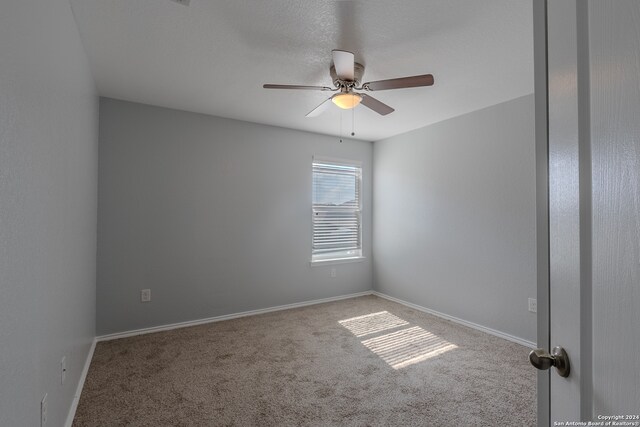 carpeted spare room with ceiling fan