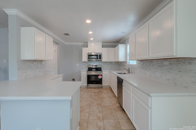 kitchen with kitchen peninsula, stainless steel appliances, ornamental molding, sink, and white cabinetry