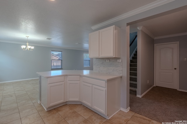 kitchen with kitchen peninsula, white cabinets, an inviting chandelier, crown molding, and light colored carpet