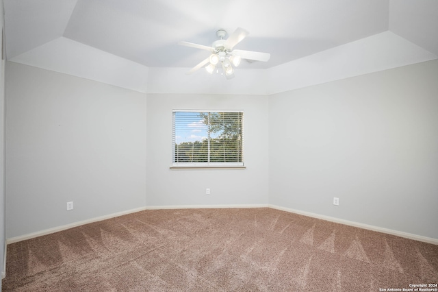 carpeted empty room with ceiling fan and a tray ceiling