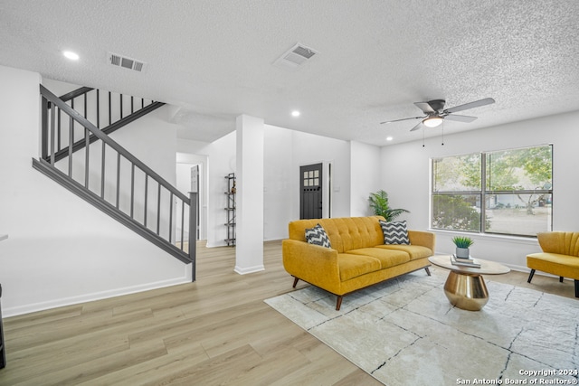 living room with light hardwood / wood-style floors, a textured ceiling, and ceiling fan